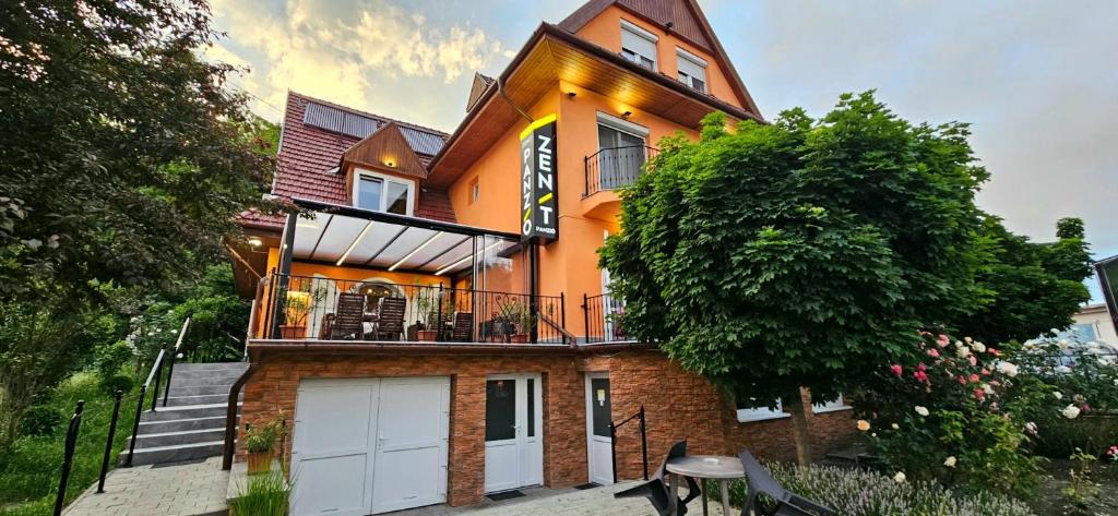 a large orange house with two white garage doors at Zenit Panzió in Miskolctapolca