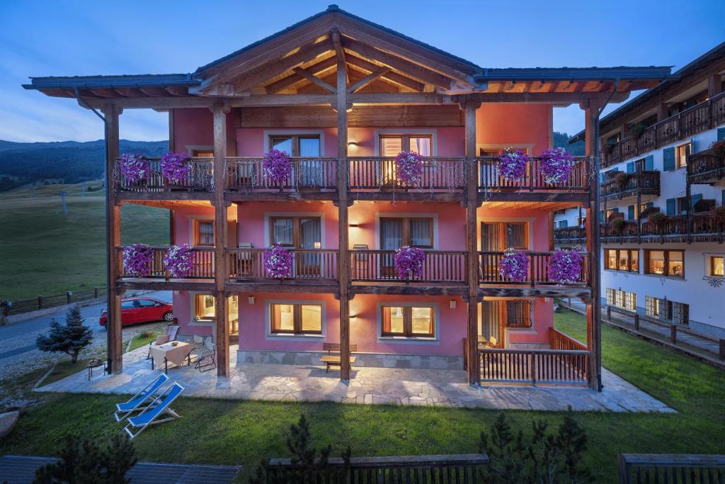 an apartment building with a balcony with purple flowers at Bio Hotel Villa Cecilia in Livigno