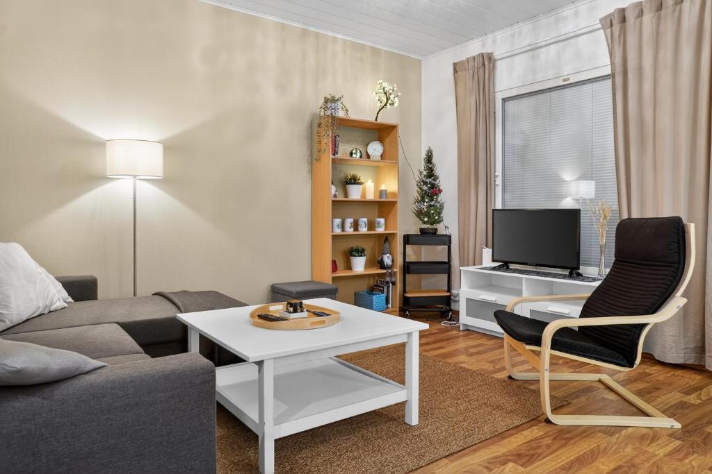 a living room with a couch and a table and a tv at Cozy two-room apartment with sauna in Sodankylä