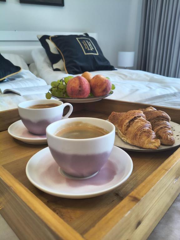 a table with two cups of coffee and plates of pastries at Mazury Glam Studio in Giżycko