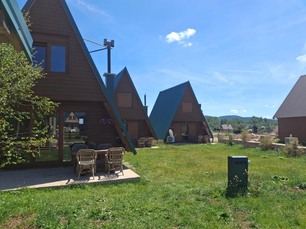 a group of houses with chairs and a table in the yard at Three Houses in Žabljak