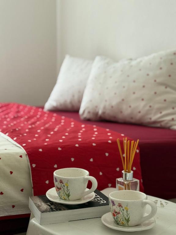 two coffee cups on a table next to a bed at Apartment Green Heaven in Konjic