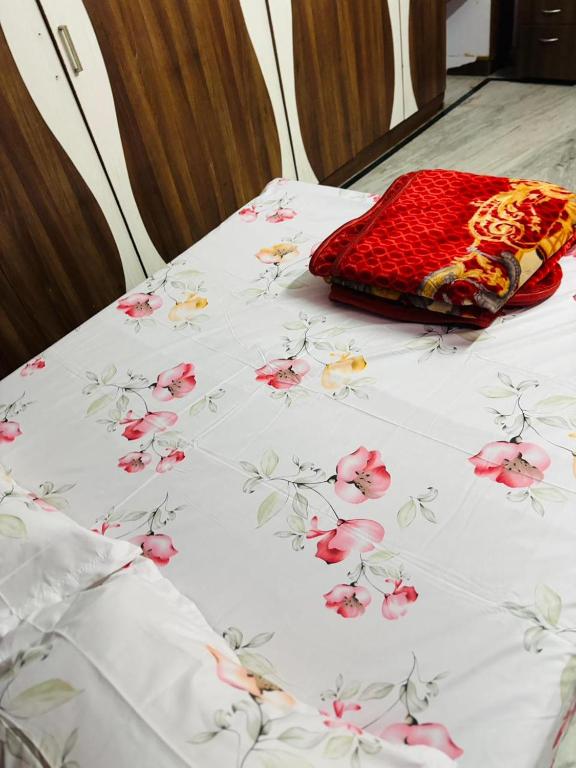 a bed with a white sheet with pink flowers on it at Lara Homestay duplex 3bhk in Secunderabad