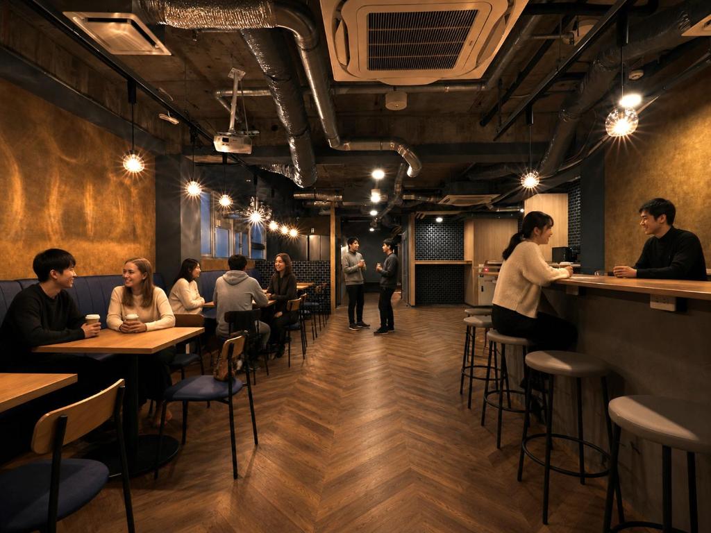 a group of people sitting at tables in a restaurant at Shijo Guesthouse HIVE in Kyoto