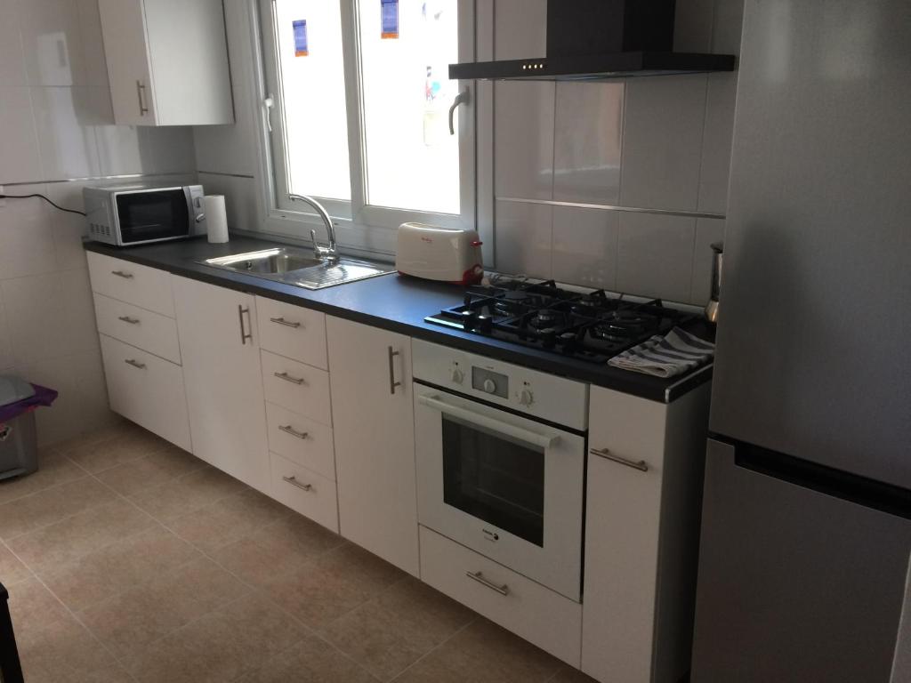 cocina con armarios blancos y fogones en Apartamento Mateos 50 por ciento dcto directo en Murcia