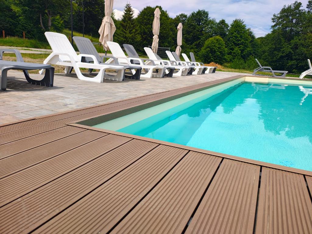 a swimming pool with white chairs and a bunch ofitures at Panorama Budești in Budeşti