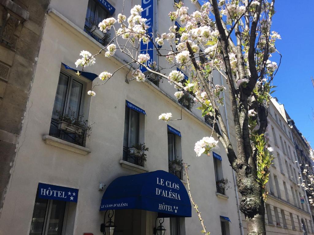 a tree in front of a building with a blue awning at Hotel Le Clos d'Alésia in Paris