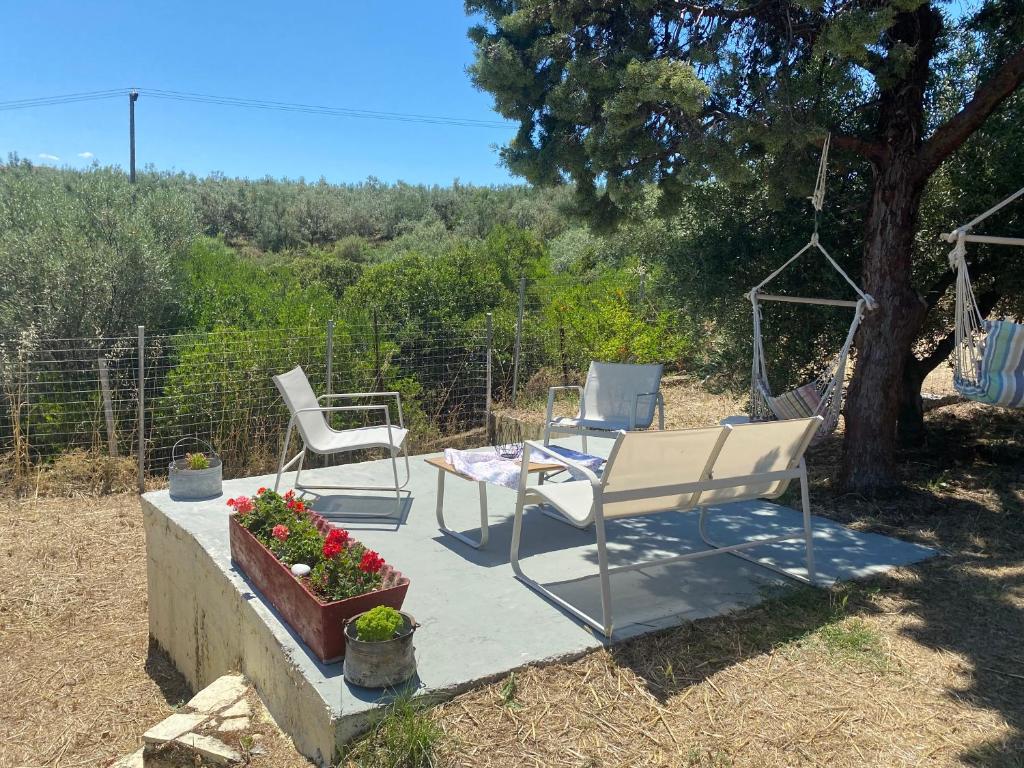 a patio with two chairs and a table and flowers at Real Holidays Antoniadou - Rustic House in Elaiokhórion