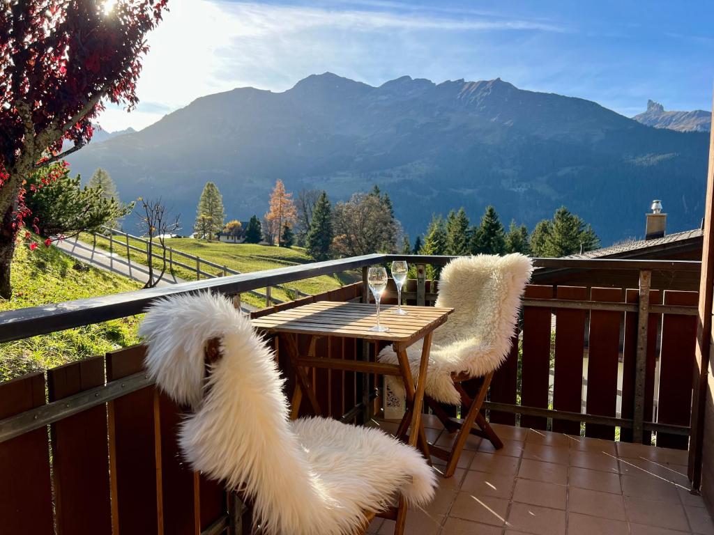 a table and two chairs on a balcony with mountains at Chalet Steinbock Wengen in Wengen