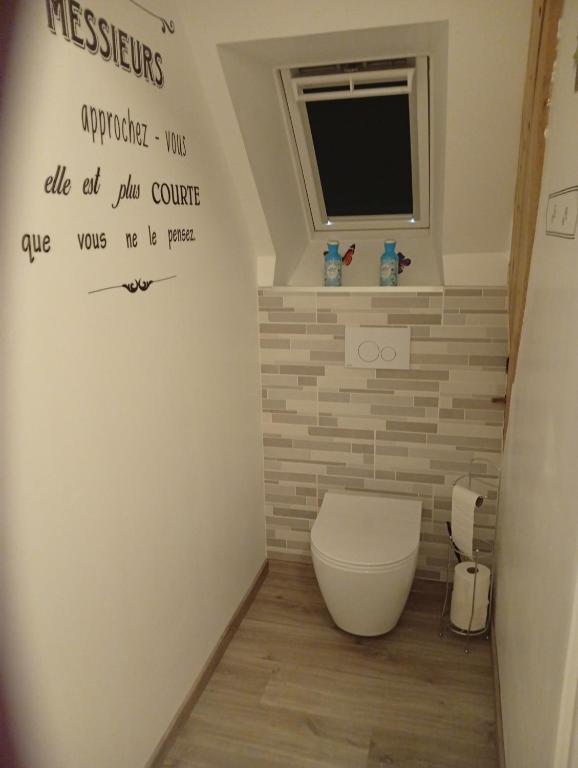 a bathroom with a toilet and a tv on the wall at Chambre familiale in Voutré