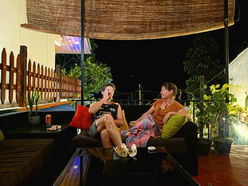 two people sitting on a couch on a patio at night at Seven Minutes Ella by SANS in Ella