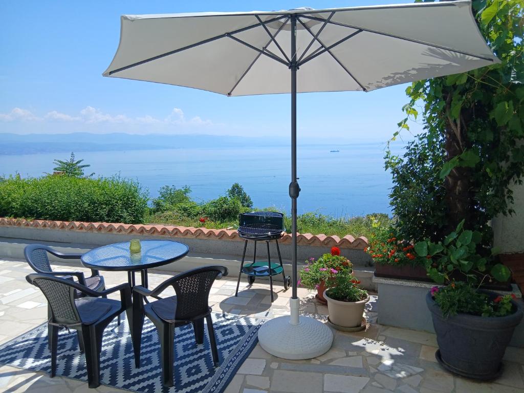 a patio with a table and chairs and an umbrella at Apartments Smokva in Opatija