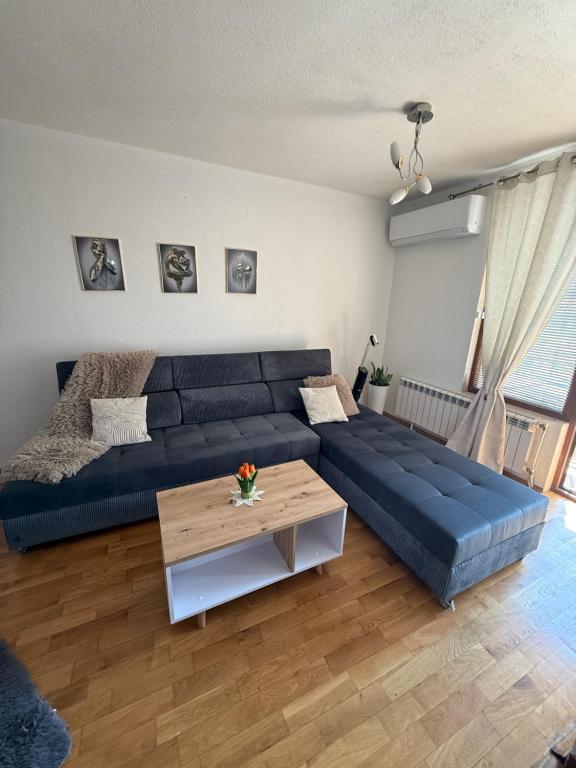 a living room with a blue couch and a table at Апартамент “Djanina 2” in Sandanski