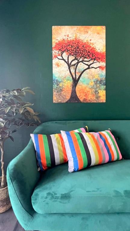 a green couch with two pillows and a painting on the wall at Vorbasse Holiday Apartments in Vorbasse