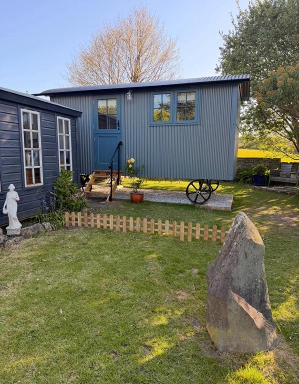 a small blue house with a rock in the yard at Shepherds Hut in St Austell