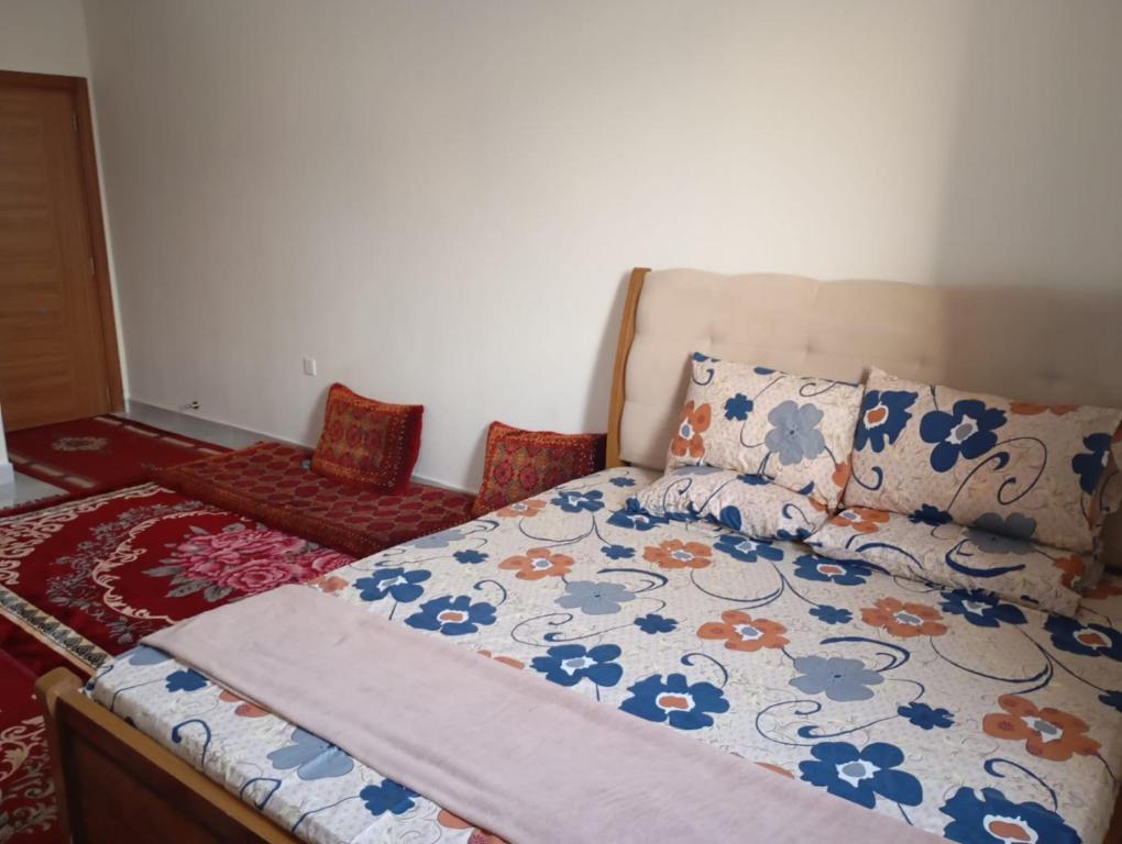 a bedroom with a bed with a floral comforter at Home Room in Ghukra