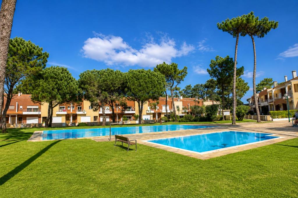 a swimming pool in a park with trees and buildings at Casa da Cuca in Fão