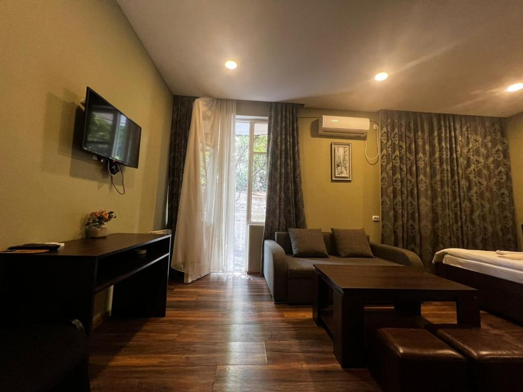 a living room with a couch and a tv at Boutique Hotel Iveria in Tbilisi City