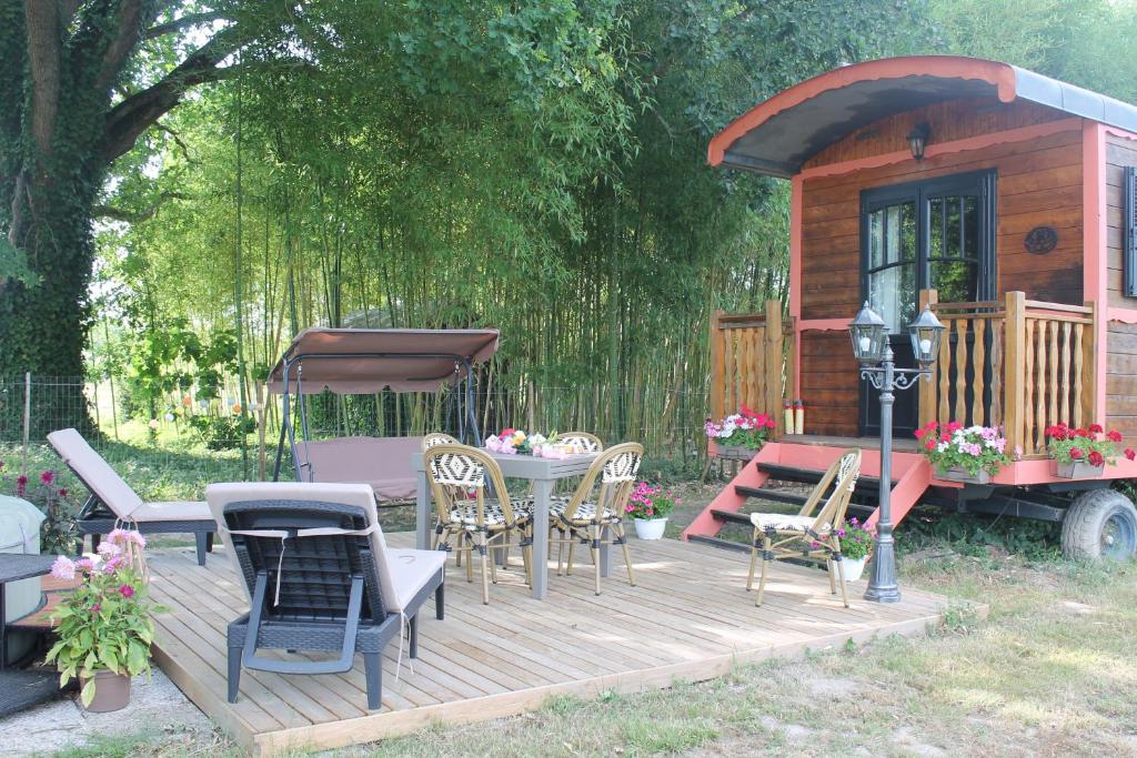 a wooden deck with chairs and a table and a house at roulotte de charme avec jacuzzi privé in Beaupouyet