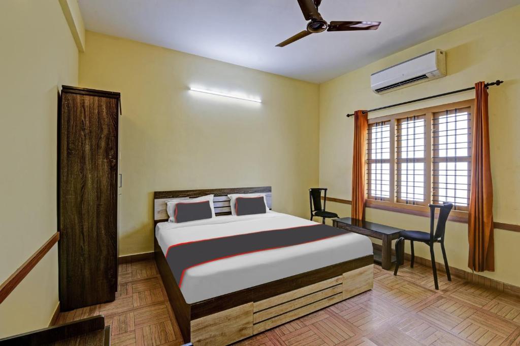 a bedroom with a bed and a chair and a window at Collection O EXPRESS SUITES in Calicut