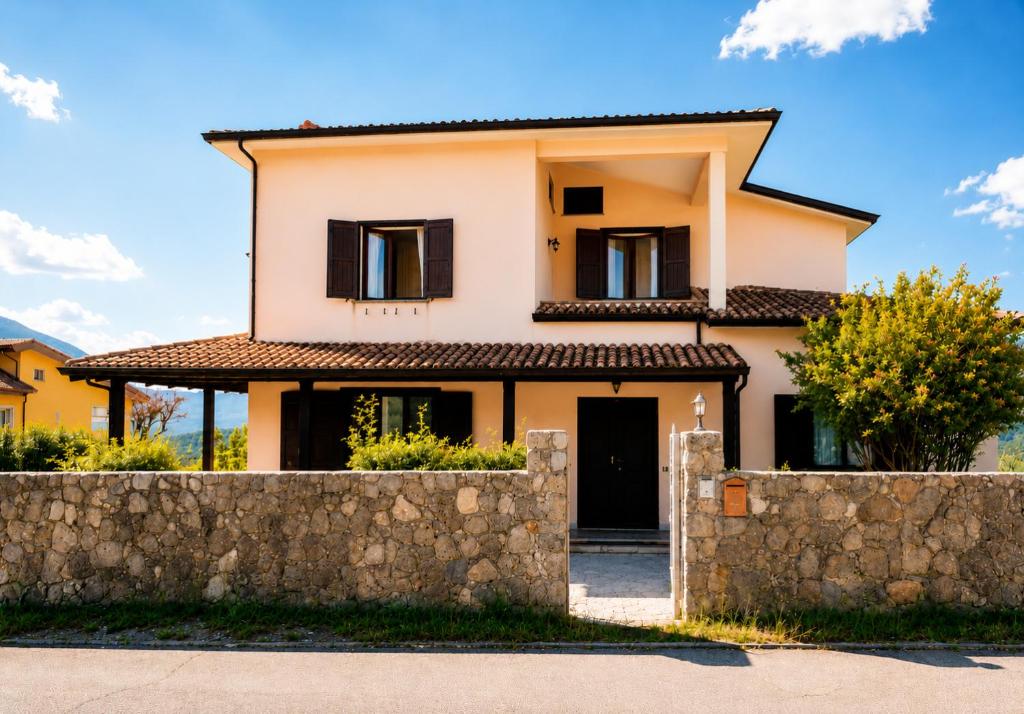 a house with a stone fence in front of it at La quercia di Massena in Lauria Inferiore