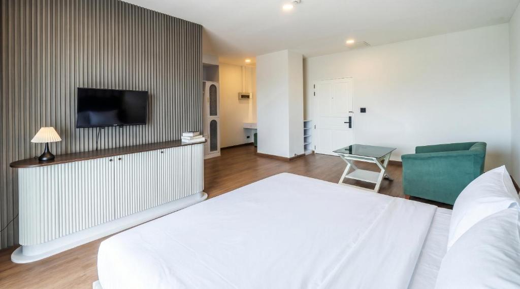 una camera d'albergo con un letto, una sedia e una televisione di Tittower a Bangkok