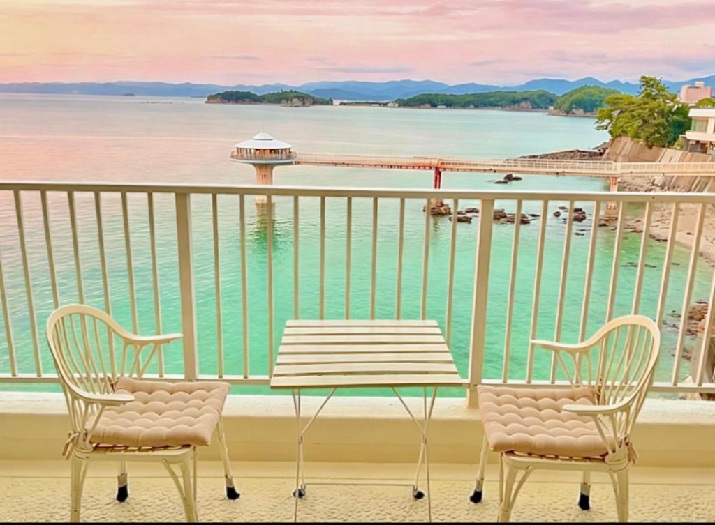 a table and chairs on a balcony with a view of the water at Ajisai Coral Princess Villa in Shirahama