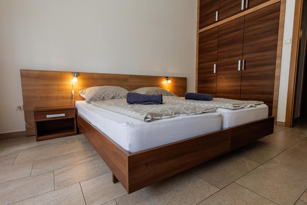 a bedroom with a large bed with a wooden headboard at Jacht Apartmanok in Balatonfüred
