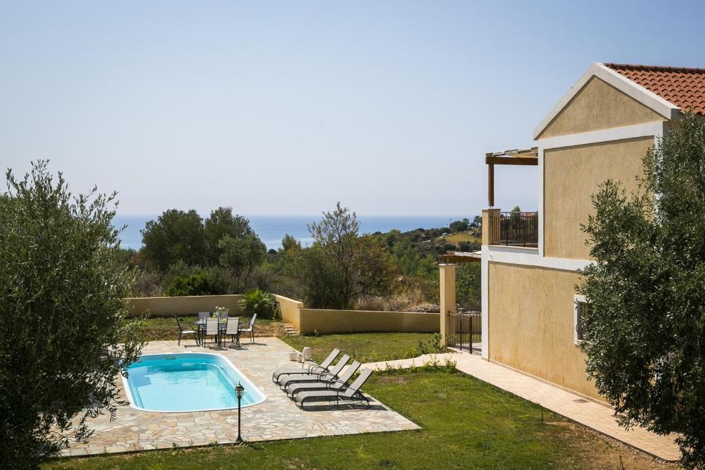 a backyard with a swimming pool and a house at Villa Karavias by Villa Select in Trapezaki