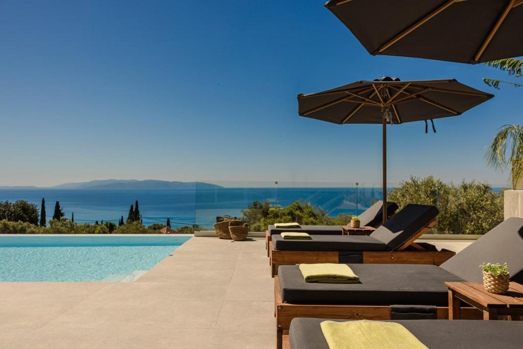 a swimming pool with lounge chairs and an umbrella at Lourdas Sunshine in Lourdata