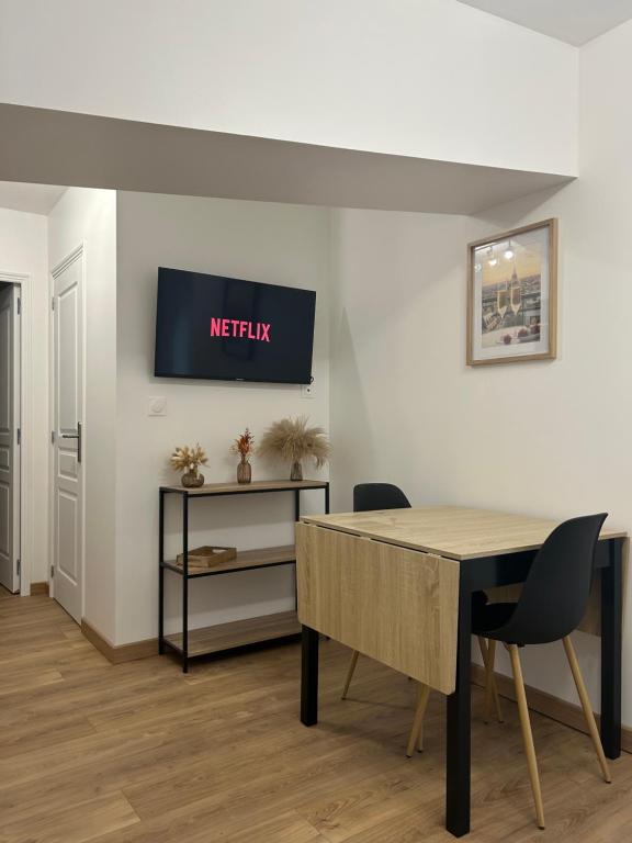 a dining room with a table and a tv on the wall at Le refuge des coteaux in Trelou Sur Marne