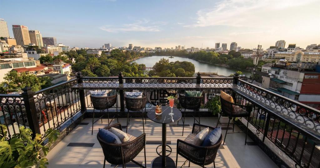 a balcony with chairs and a table with a view of a river at Hoan Kiem Legend Ha Noi Hotel in Hanoi