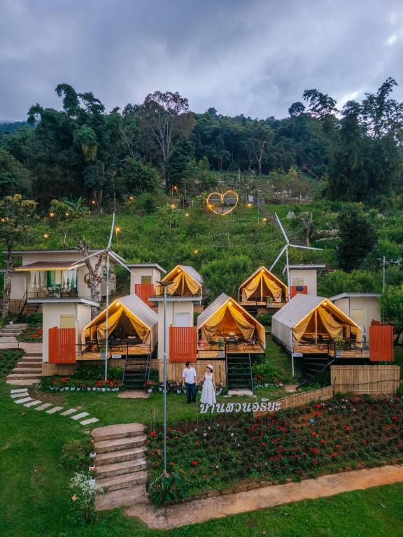 a group of tents on a hill with people standing outside at Bansuanariya บ้านสวนอริยะ in Ban Na Yang