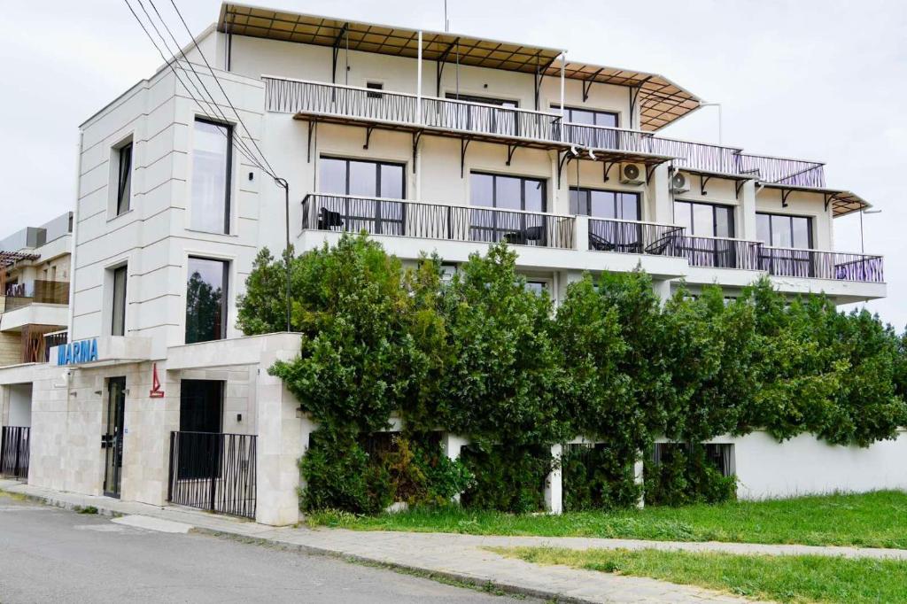 a white building with a tree in front of it at Marina Sarafovo by Cosher in Burgas