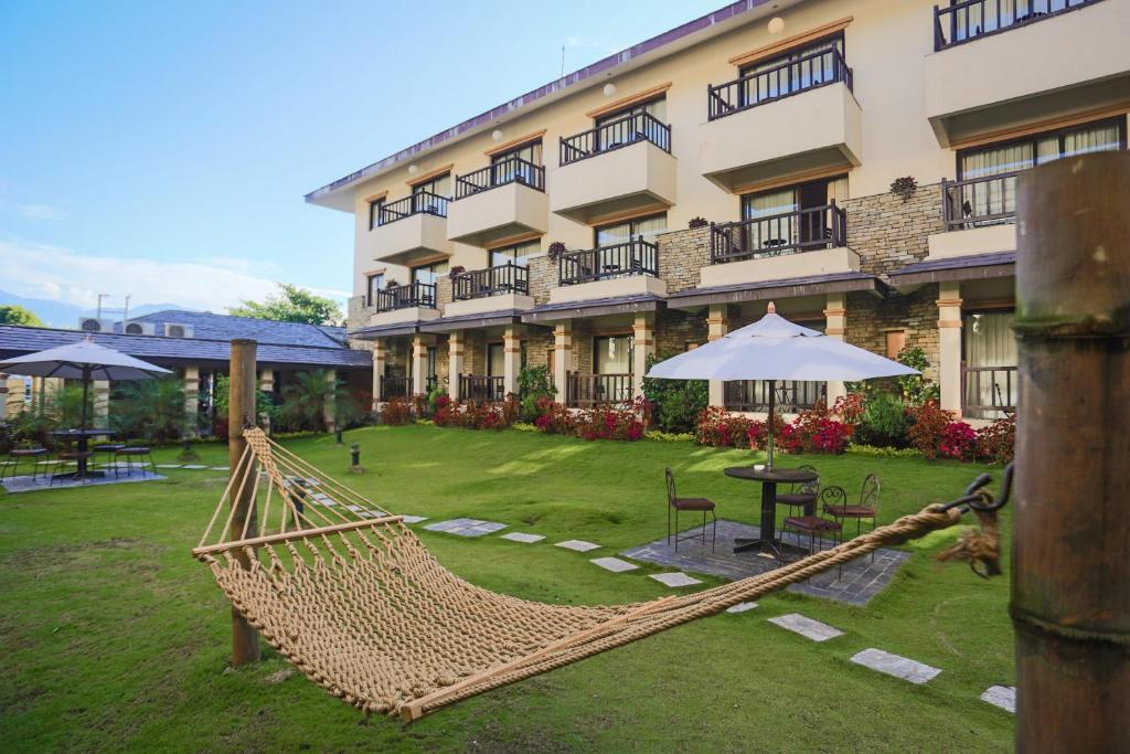 a resort with a hammock in front of a building at Atithi Resort & Spa in Pokhara