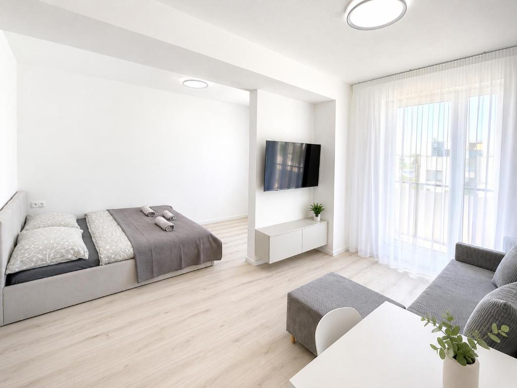 a white bedroom with a bed and a tv at Luxury White Residence in Trenčín