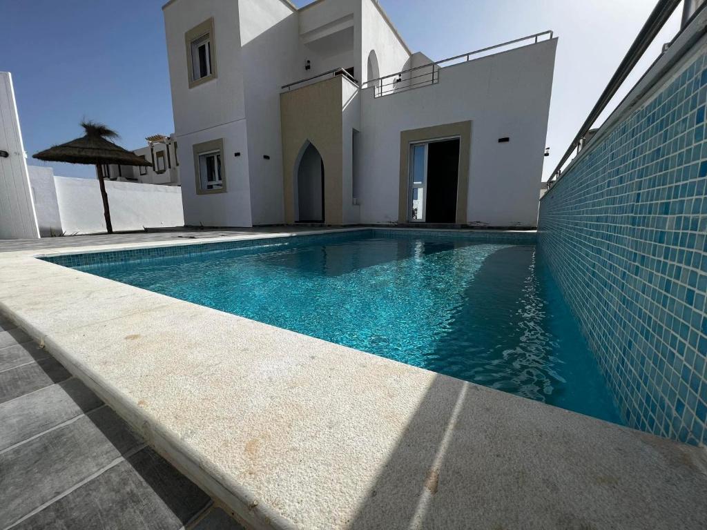 a swimming pool in front of a house at Villa baya in Djerba