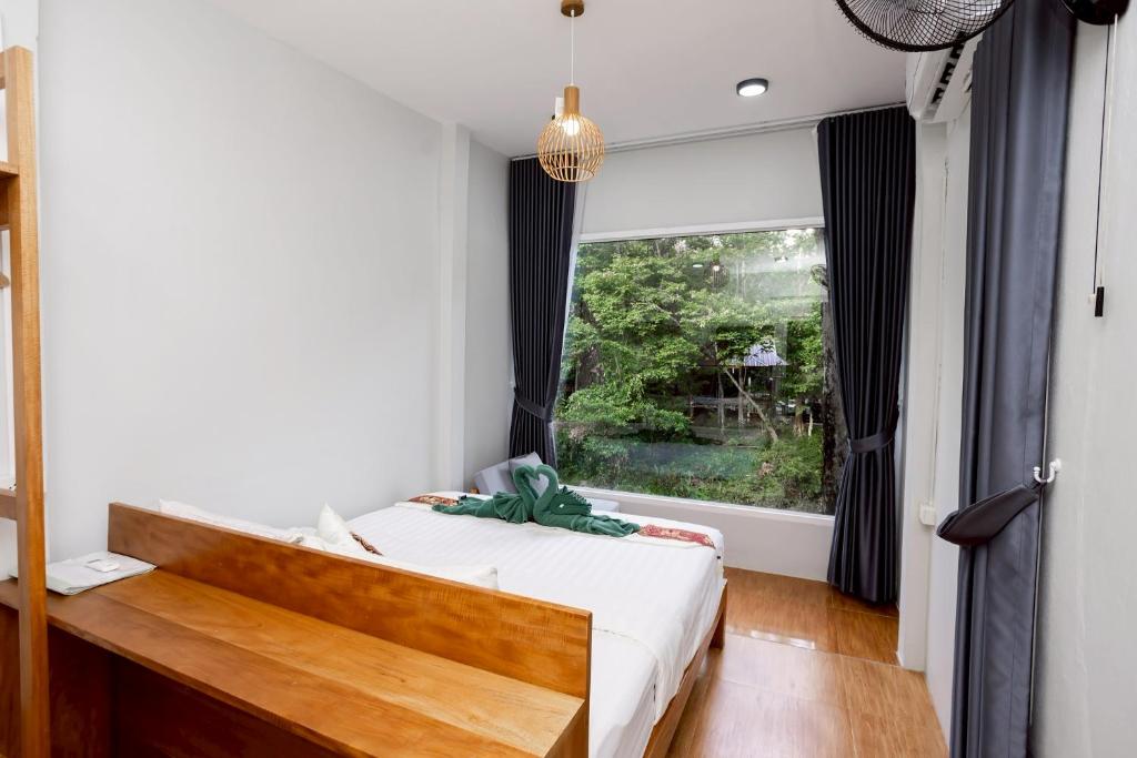 a bedroom with a bed and a large window at Khao Sok Jungle Huts Resort in Khao Sok National Park