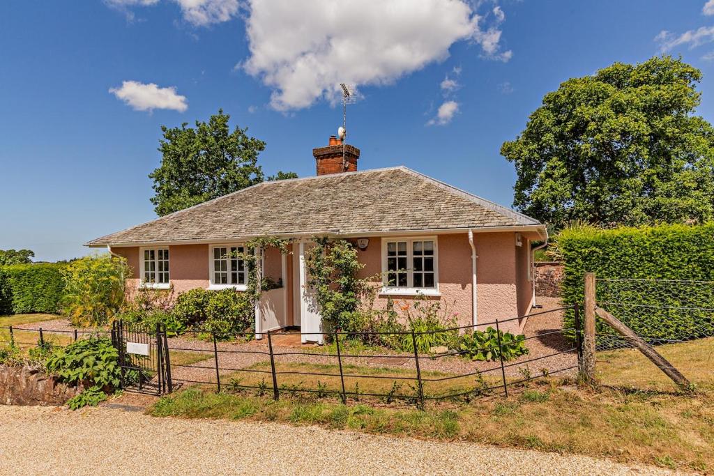 a pink house with a fence in front of it at Recently renovated Lodge Cottage, Quantocks in West Bagborough