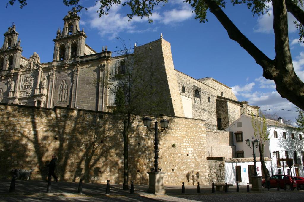 un antiguo edificio de piedra con una iglesia en el fondo en Hostal Santa María de Úbeda, en Úbeda