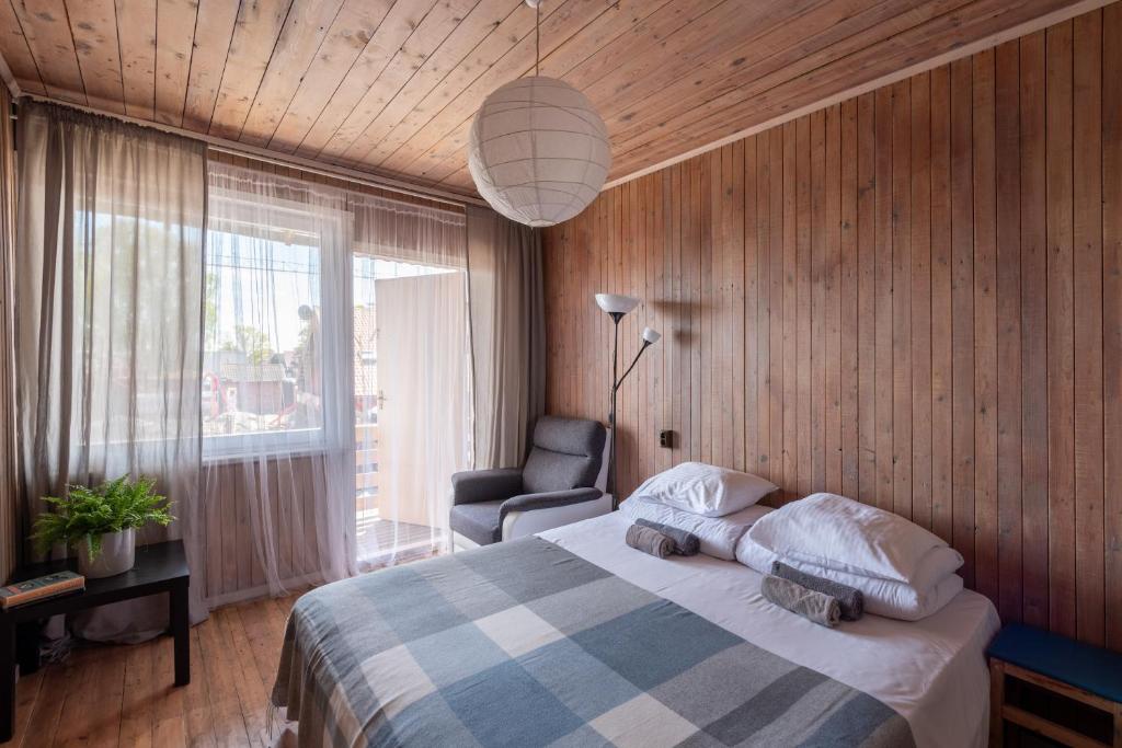 ein Schlafzimmer mit einem Bett, einem Stuhl und einem Fenster in der Unterkunft Zunda in Nida
