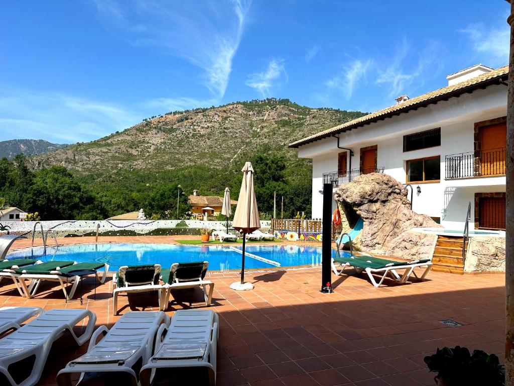 ein Schwimmbad mit Liegestühlen und ein Gebäude in der Unterkunft Gran Hotel Spa Parque de Cazorla in Arroyo Frio