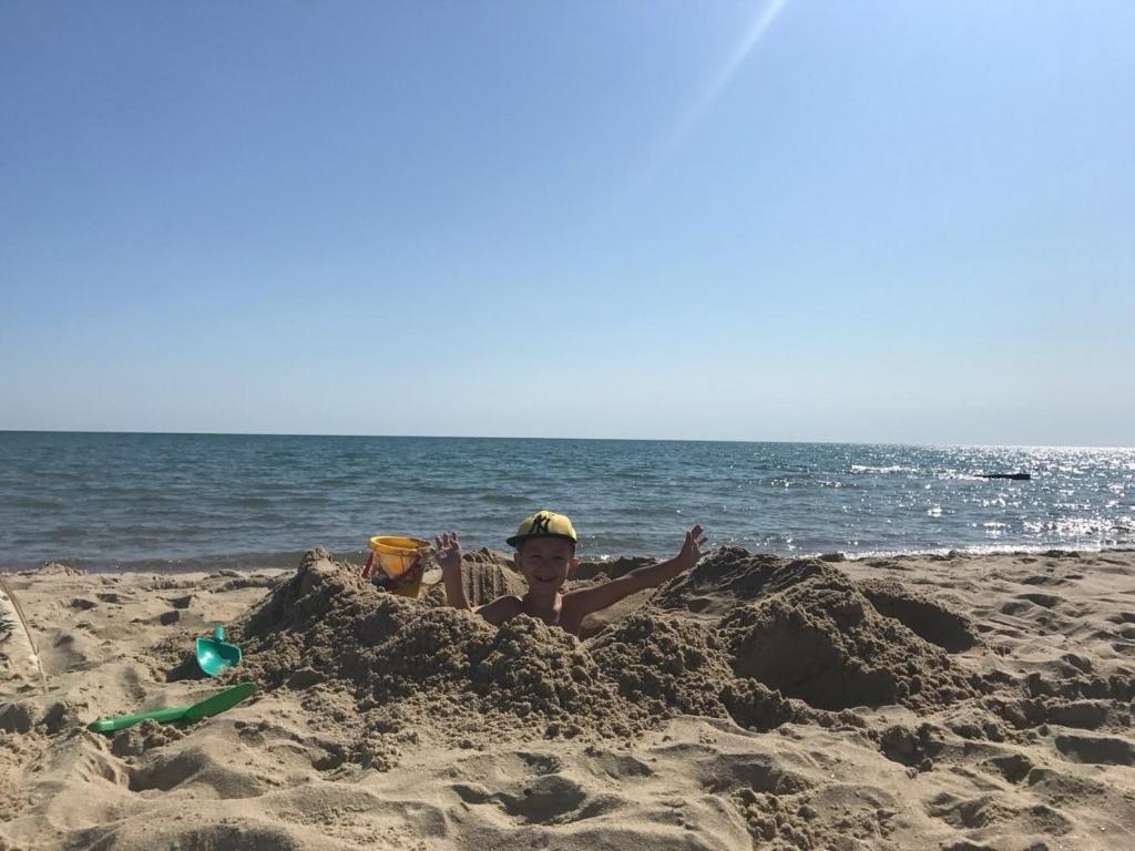 a young boy laying in a sand castle on the beach at Villa Bossa in Zatoka