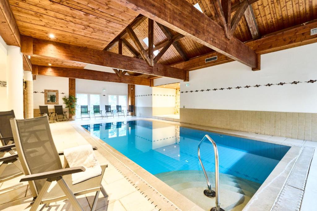 an indoor pool with blue water and wooden ceilings at Logis Hotel Domaine de Rouffach in Rouffach