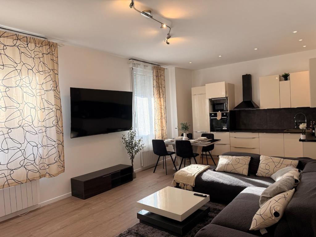 a living room with a couch and a table and a kitchen at Superbe 4 pièces luxueux in Fleury-les-Aubrais