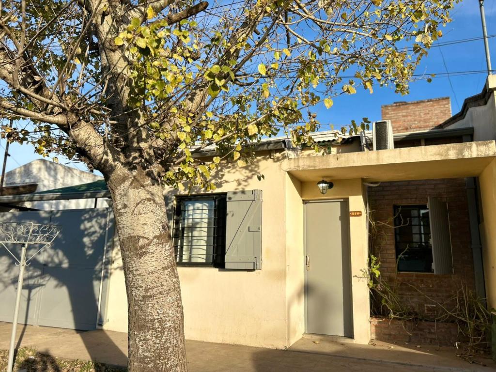a white house with a tree in front of it at La Casita de Levene en Lobos in Lobos