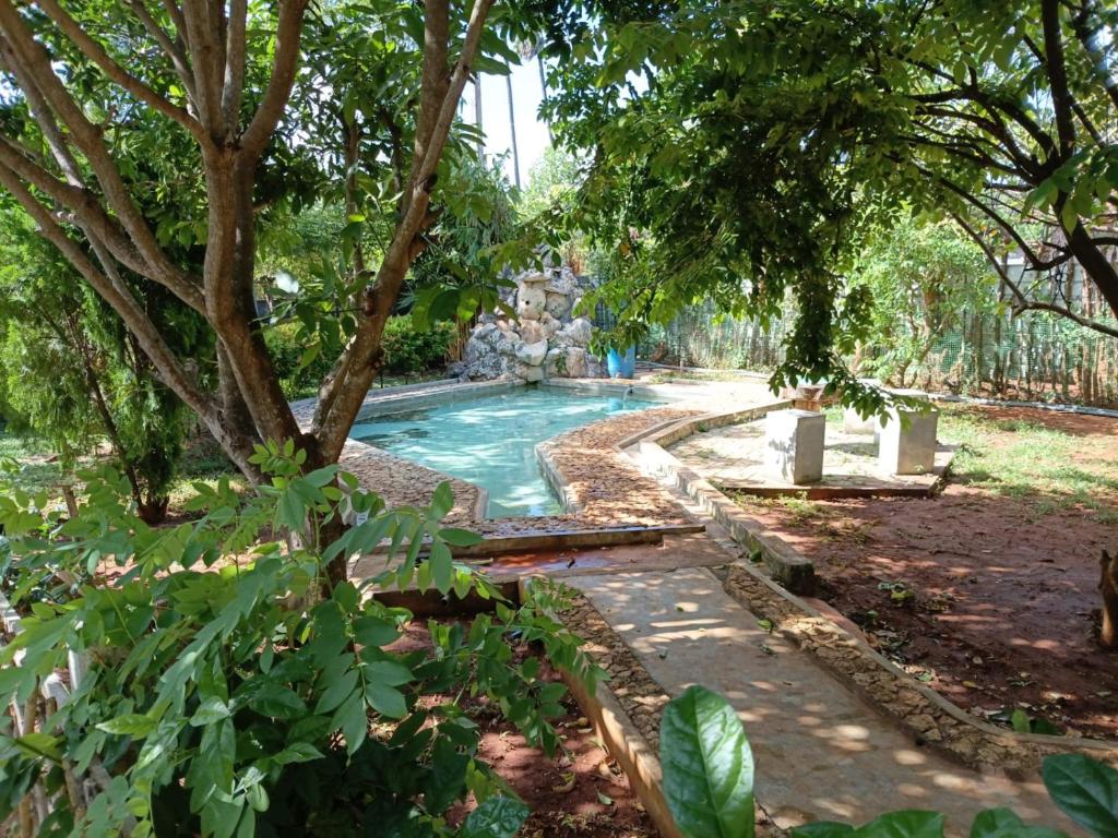 a swimming pool in a garden with trees at Aachchi Country Home by ABC Leisure's group in Jaffna