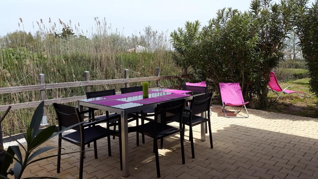 a table and chairs on a patio with pink chairs at Mazet L'étrier in Saintes-Maries-de-la-Mer