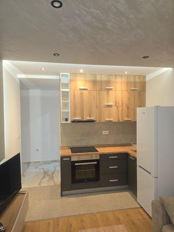 a kitchen with wooden cabinets and a white refrigerator at Sofija in Radanovići