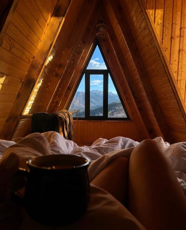 a woman laying in bed with a cup of coffee at HillSide Cottage-ჰილსაიდ კოტეჯი in K'eda